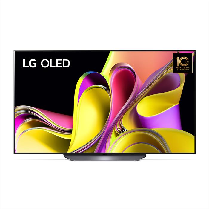 Una TV LG OLED è appesa a una parete bianca in un soggiorno elegante, con un divano grigio e un tappeto chiaro. La stanza è ben illuminata e decorata con piante verdi.