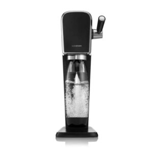 Un elegante distributore di acqua frizzante in acciaio nero è posto su un tavolo di legno chiaro. Accanto, ci sono bicchieri trasparenti e una bottiglia d'acqua.